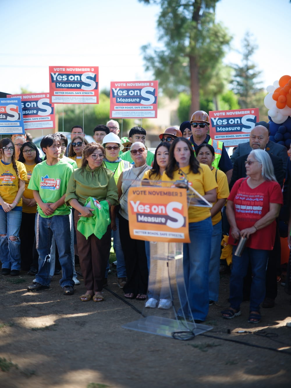 Young woman speaks beside workers and community members supporting Measure S investments in road repairs, public transit, and local jobs.