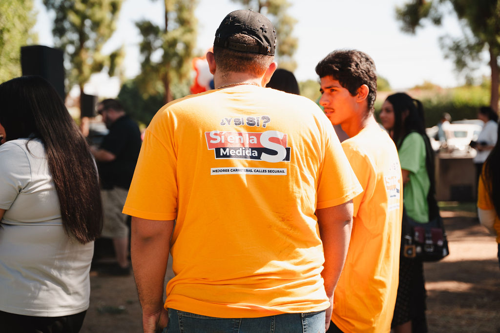 Young Measure S supporters gather in bilingual campaign shirts promoting better roads, safer streets, and modern transportation.