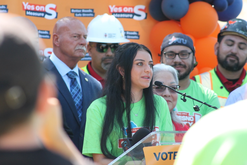 Young woman speaks alongside construction workers and community leaders supporting Measure S transportation investments and local jobs.